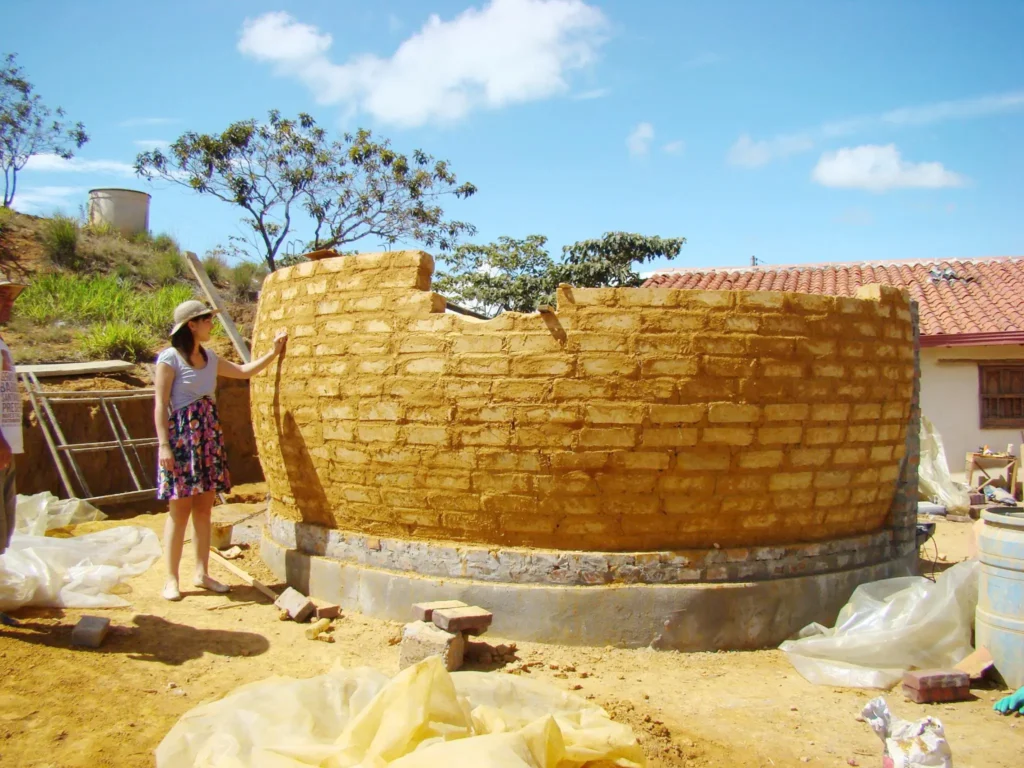 Cúpula de tierra en construcción, técnica artesanal y materiales locales.